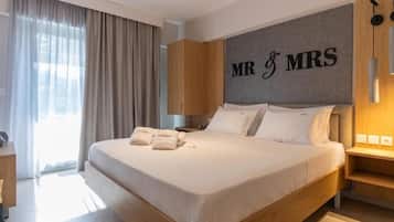 A hotel room with a large bed, a headboard with 'MR & MRS' lettering, a wooden wardrobe, and a bedside table with a lamp.
