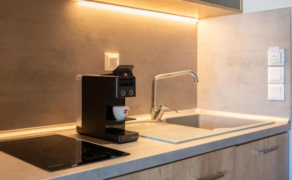 Et moderne køkken med indbygget kaffemaskine, vask og bordplade.