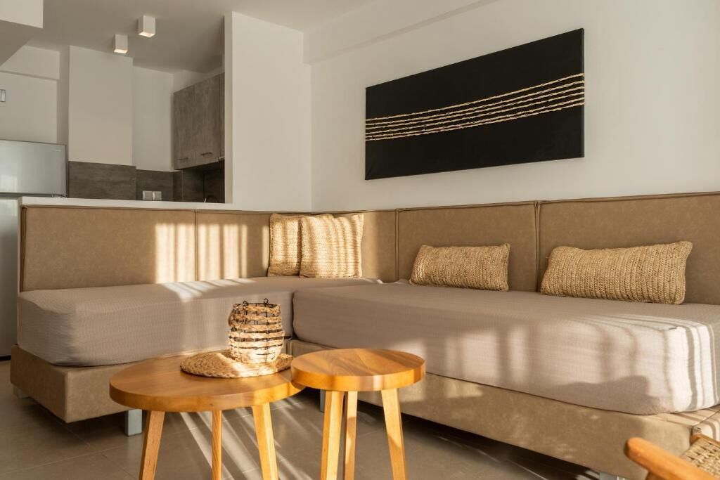 Una sala de estar moderna con un sofá, dos mesitas de madera y un cuadro abstracto negro en la pared.