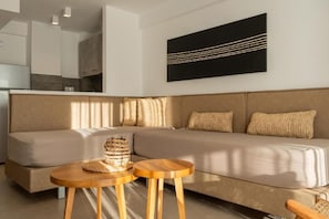 A modern living room with a sofa, two wooden side tables, and a black abstract painting on the wall. - SARTI PREMIUM LUXURY SUITES (SITHONIA)