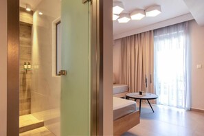 Une salle de bain moderne avec une douche et des toilettes séparées. On y trouve un lit avec une table de chevet et une fenêtre avec des rideaux.