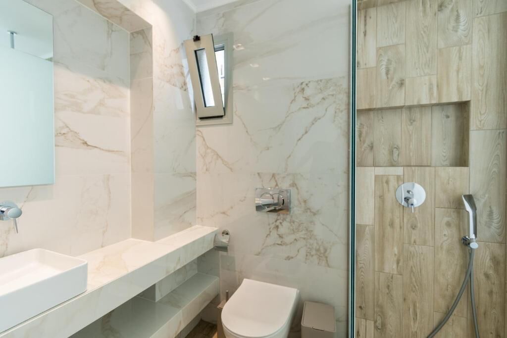 Un baño moderno con tocador de mármol, inodoro y zona de ducha.