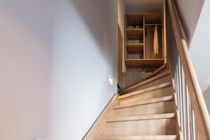 A wooden staircase with a handrail, leading to a room with a wooden floor and a white wall. - SARTI PREMIUM LUXURY SUITES (SITHONIA)