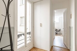Ein Korridor mit einem weißen Kleiderschrank, einer Tür zu einem Balkon und einem Essbereich mit Stühlen und einem Tisch.