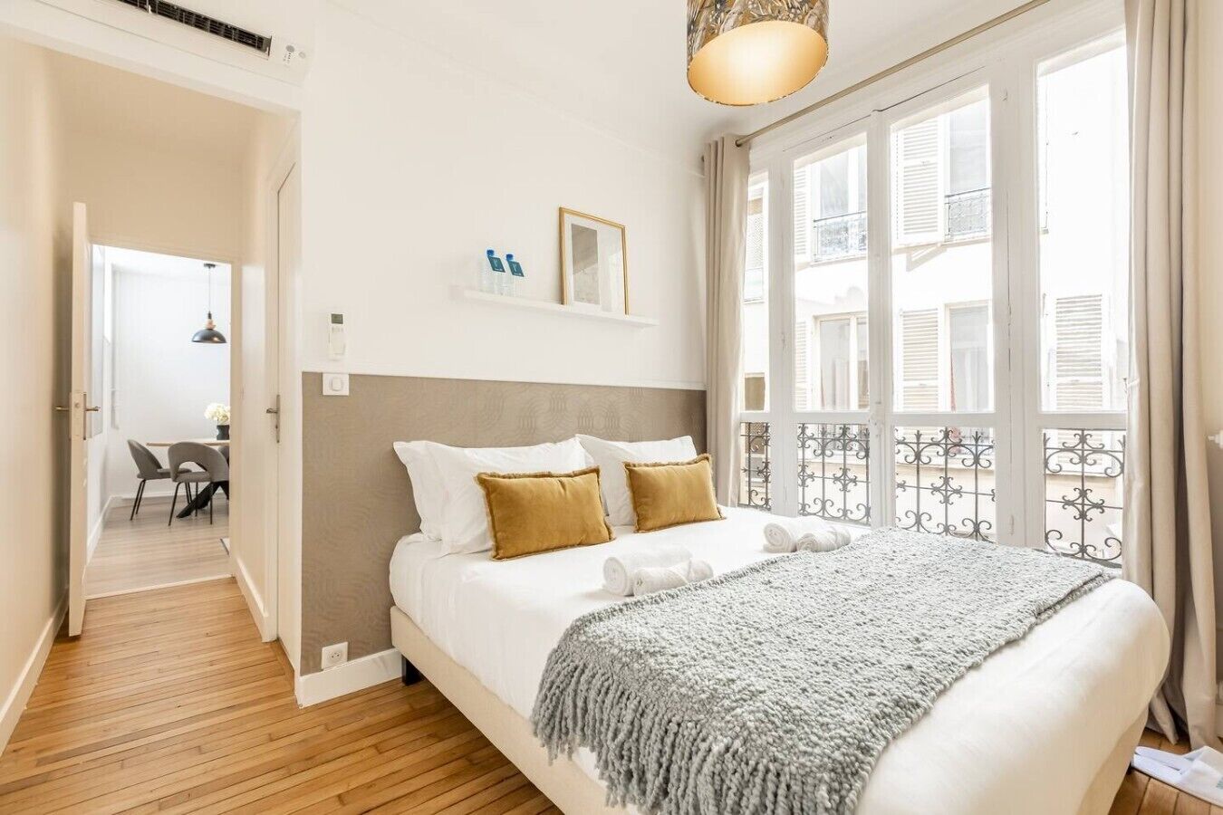 A bedroom with a bed, a bedside table, a window with a view, and a door leading to a balcony.