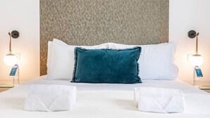 Habitación de hotel con cama, dos lámparas de noche y una pared con textura detrás de la cama.