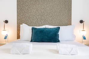 Ein Hotelzimmer mit einem Bett, zwei Nachttischlampen und einer strukturierten Wand dahinter.