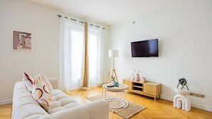 A modern living room with a sofa, a coffee table, a lamp, a TV, and a small cabinet. - Heart of Paris, 2-Bedroom Apartment, Arts et Métiers, Marais (Paris)