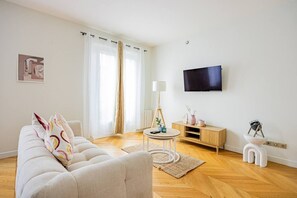 A modern living room with a sofa, a coffee table, a lamp, a TV, and a small cabinet. - Heart of Paris, 2-Bedroom Apartment, Arts et Métiers, Marais (Paris)