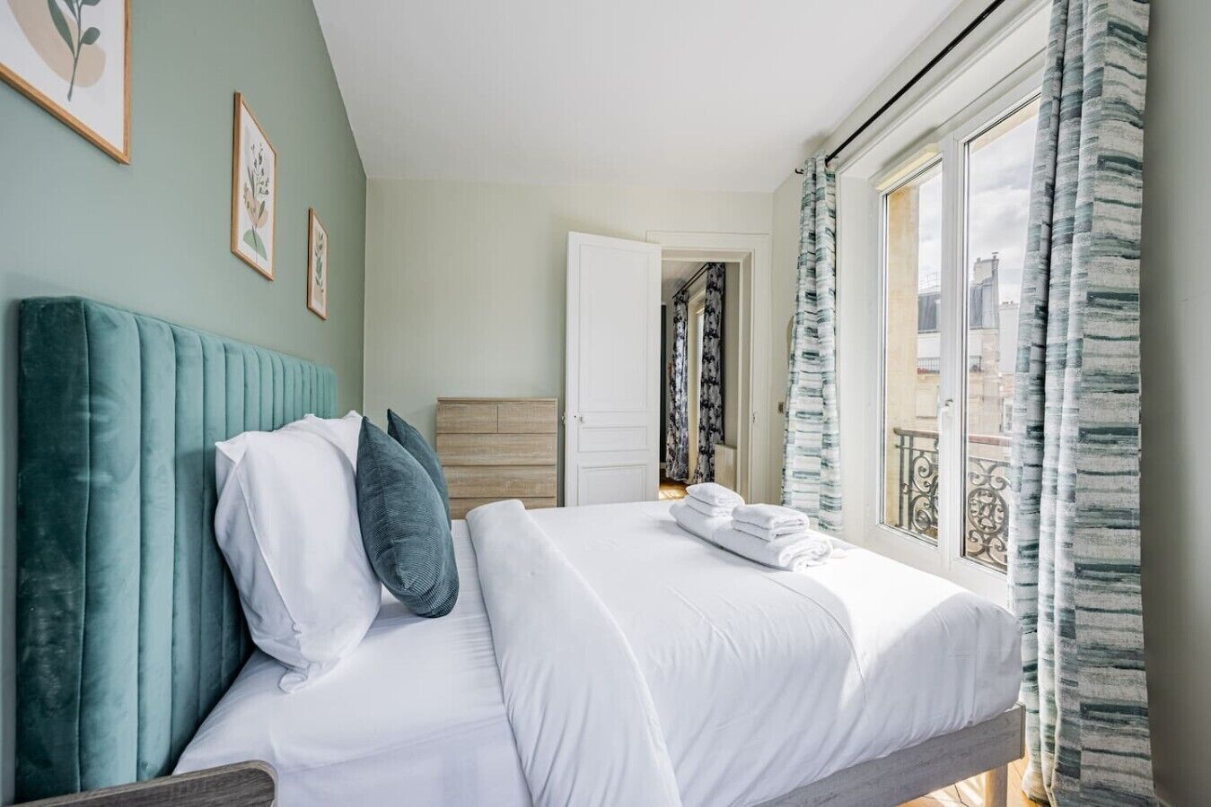 Ein Hotelzimmer mit Bett, Kopfteil, Kleiderschrank und Blick auf die Stadt durch das Fenster.