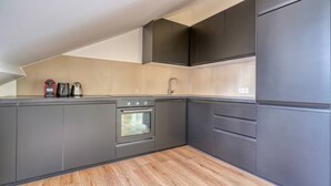 A modern kitchen with dark cabinetry, a built-in oven, and a wooden floor. - 4G. 3-Bedroom Apartment for 6 People, Paris 15th Arrondissement, AC (Paris)