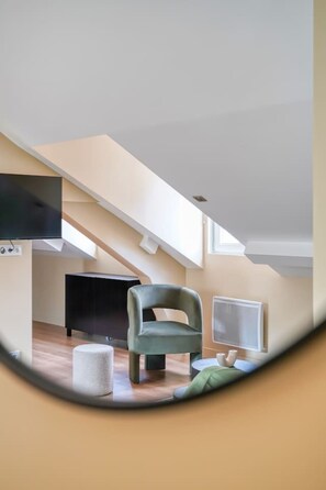 A modern living room with a high ceiling, a flat-screen TV, a green armchair, and a small round table. - 4G. 3-Bedroom Apartment for 6 People, Paris 15th Arrondissement, AC (Paris)