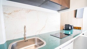 A modern kitchen with a stainless steel sink, a glass countertop, and a built-in range hood. - Studio for 2 People - Hotel de Ville - Marais - Paris 04 - Central (Paris)