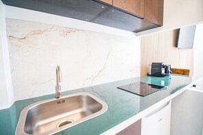 Eine moderne Küche mit einer Spüle aus Edelstahl, einer Glasarbeitsplatte und einer eingebauten Dunstabzugshaube.