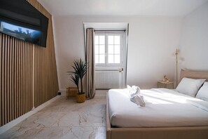 Ein Hotelzimmer mit einem Bett, einer Zimmerpflanze, einem Fernseher, einem Fenster mit Vorhängen und einer Heizung.
