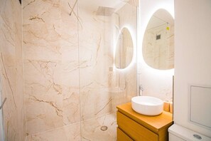 Ein Badezimmer mit Marmorwand, einem runden Waschbecken und einem Spiegel.
