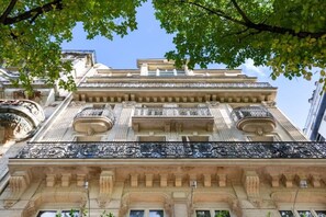 Um edifício com arquitetura clássica, com varandas ornamentadas e detalhada fachada de pedra.
