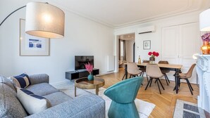 A modern living room with a sofa, a coffee table, and a dining area with chairs and a table. - A4.Premium-Arc de Triomphe-Champs-Élysées-3 Bedrooms (Paris)