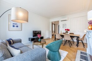 Uma sala de estar moderna com um sofá, uma mesa de centro e uma área de jantar com cadeiras e uma mesa.