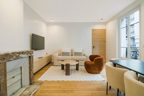 Ein modernes Wohnzimmer mit einer Couch, Sesseln, einem Couchtisch und einem Kamin.