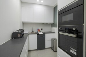 A compact kitchen with a built-in oven, a coffee machine, and a trash bin. - Premium Suites - Arc de Triomphe - Trocadéro (Paris)