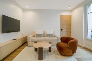 Ein modernes Wohnzimmer mit einer Couch, einem runden Couchtisch und einem einzelnen Sessel.