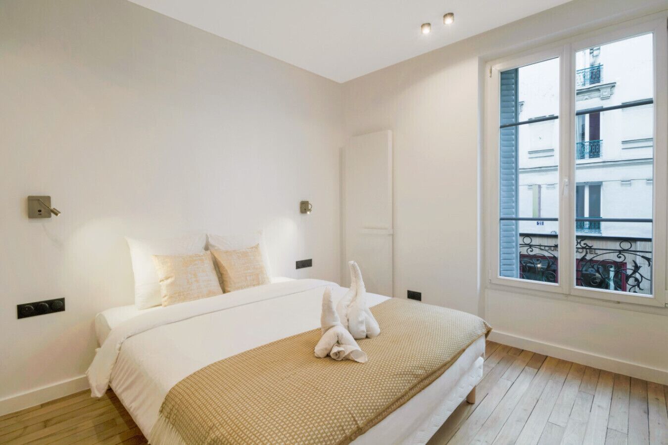 A bedroom with a bed, a window, and a view of buildings outside.