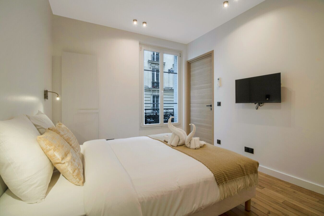 Ein Schlafzimmer mit Bett, Fenster, Fernseher und Tür.