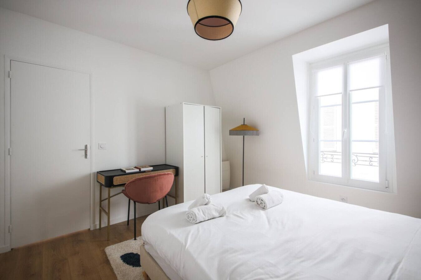 Une chambre à coucher avec un lit, un bureau, une chaise, une armoire et une fenêtre.