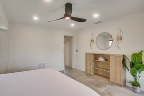 A bedroom with a bed, a ceiling fan, a mirror, and a wooden wardrobe. - Fishing Dock & Lanai! Myakka River Family Retreat (Port Charlotte)