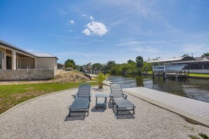 A waterfront property with a gravel patio, lounge chairs, and a dock extending into a body of water. - Fishing Dock & Lanai! Myakka River Family Retreat (Port Charlotte)