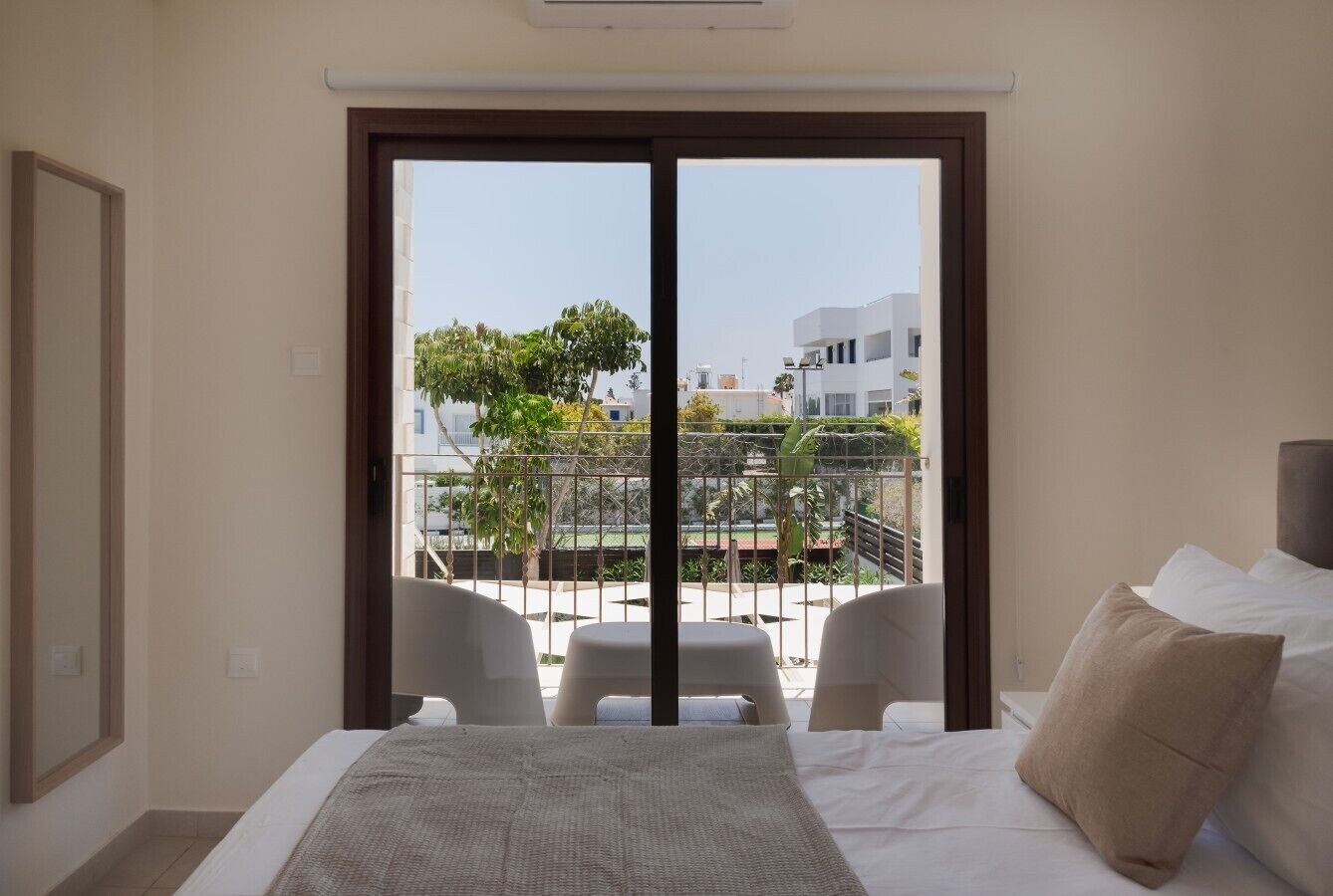 Ein Hotelzimmer mit Bett, Blick ins Freie und einem Balkon mit Stühlen.
