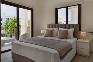 A bedroom with a large bed, two bedside tables, and a view of the outdoors. - Phaedrus Living: Luxury Villa Green Bay (Paralimni)