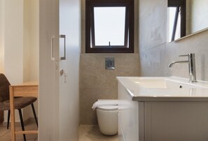 A bathroom with a toilet, sink, and a window above the toilet. - Phaedrus Living: Luxury Villa Green Bay (Paralimni)