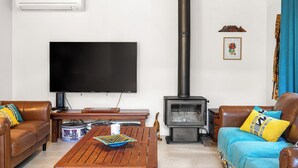 Un soggiorno con una TV a schermo piatto, un camino a legna, un tavolino da caffè con una ciotola decorativa e due divani in pelle con cuscini decorati.