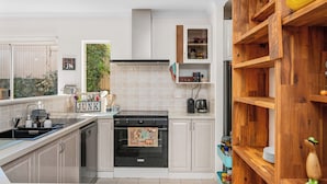 Una cucina moderna con piano cottura, lavello e mensole in legno.