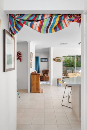 A spacious room with a tiled floor, a wooden cabinet, a brown leather chair, a dining table with chairs, and a window with a view of greenery. - Riverside Retreat Near Curtin Uni & Lo Quay Café (Wilson)
