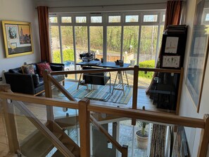 A spacious living area with a black leather sofa, a dining table, and a staircase leading to an upper level. - Outstanding contemporary country house, close to Bath with stunning views. (Bath)