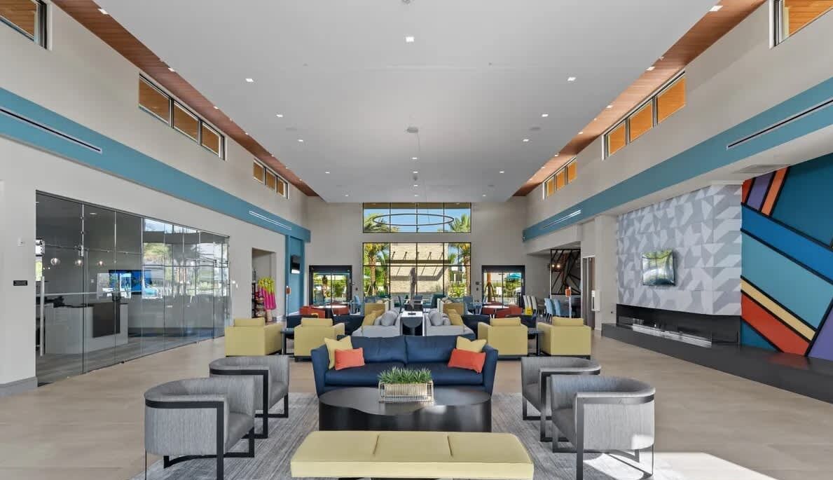 A spacious lobby with a central seating area, a reception desk, and a large window providing a view of the outdoors.