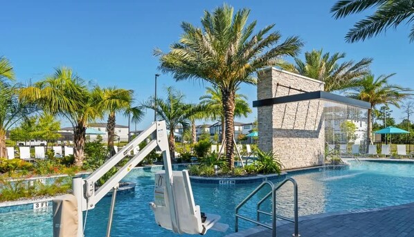 Una piscina con una postazione di salvataggio, palme e un edificio in pietra.