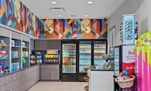 Un bar con ripiani pieni di snack e bevande assortite, un frigorifero con bevande e una macchina distributrice.