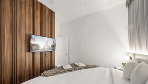 Ein Hotelzimmer mit einem Bett, einem an einer Holzvertäfelung befestigten Fernseher und einer Tür.
