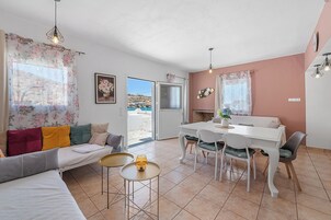 Un salón moderno con sofá, mesa de comedor y sillas, chimenea y vistas al exterior.