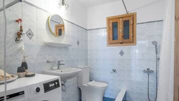 Un baño moderno con lavadora, lavabo, inodoro y zona de ducha.