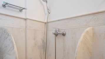 A bathroom with a shower, a towel rack, and a window.