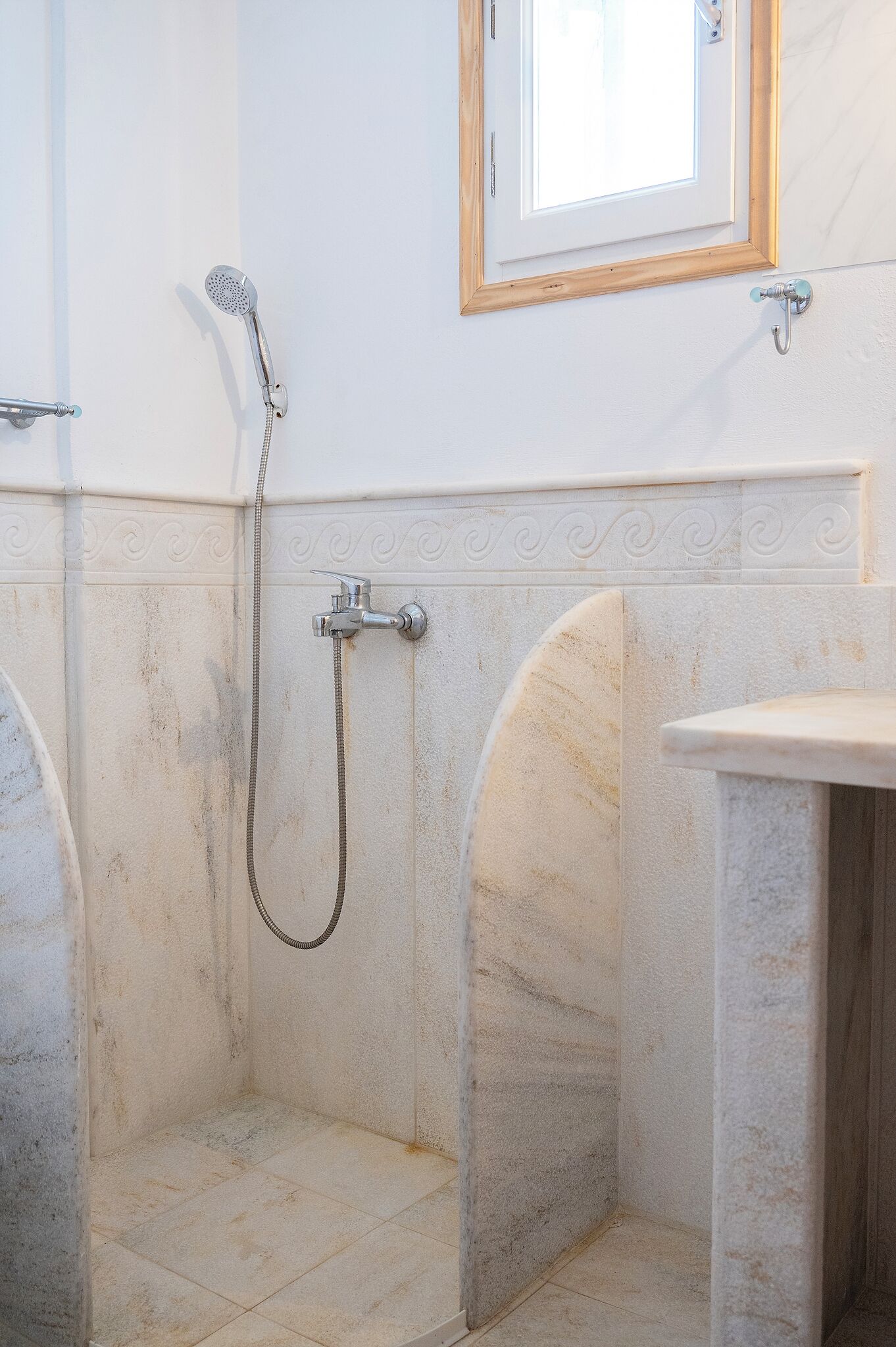 A bathroom with a shower, a sink, and a window.