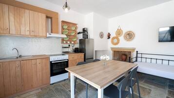 A modern kitchen with wooden cabinets, a stove, a refrigerator, and a dining table with chairs.