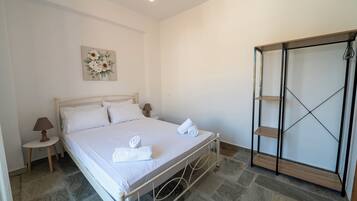 A bedroom with a bed, a bedside table with a lamp, a wall-mounted artwork, and a wardrobe with a mirrored door.