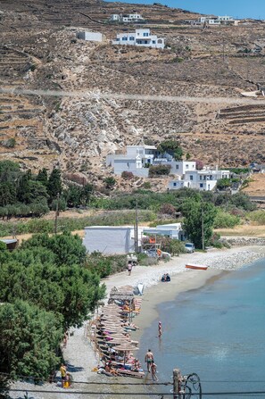 A coastal area with a beach, a row of beach umbrellas, and a few people.