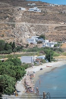 Zona costera con playa, una hilera de sombrillas y algunas personas.